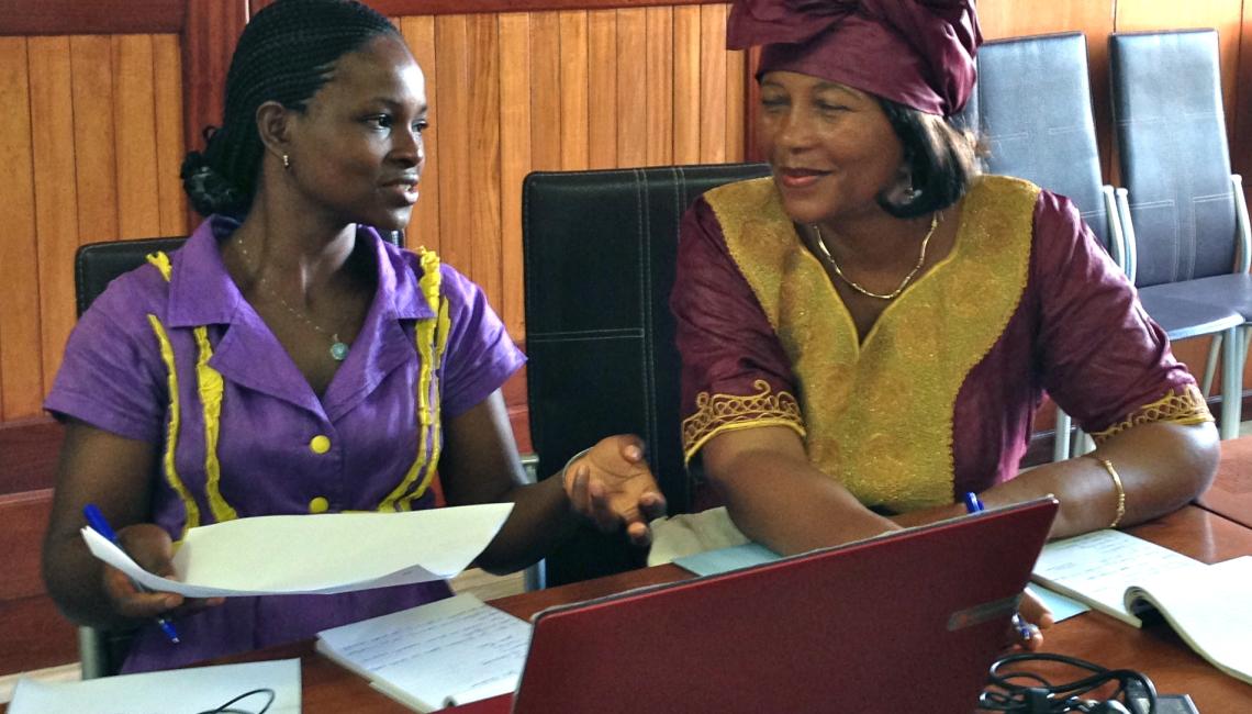 Cameroon: Two women discussing in front of a laptop.